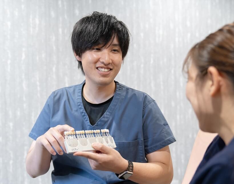 患者さまにシェードガイド（色見本）を見せる歯科医師の幸田さん