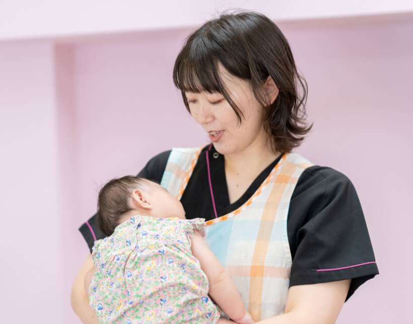子どもを抱っこする保育士の山下さん
